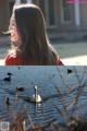 A woman in a red jacket is looking at ducks in the water.