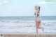 A woman in a bikini holding a sword on the beach.