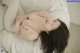 A woman laying on top of a bed in a pink bra.