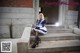 A woman in a blue and white dress sitting on some steps.