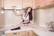 A woman sitting on top of a kitchen counter holding a knife.