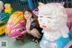 A young girl sitting on top of a toy car.