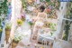 A woman in a white lingerie standing in front of a table with flowers.