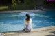 A woman sitting on the edge of a swimming pool.