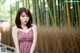 A woman in a red dress standing in front of a bamboo fence.