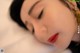 A woman laying down with her eyes closed and her head resting on a pillow.