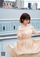 A woman in a beige dress is dancing on a rooftop.