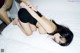 A woman laying on top of a white bed.