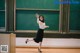 A woman in a white shirt and black skirt standing in front of a blackboard.